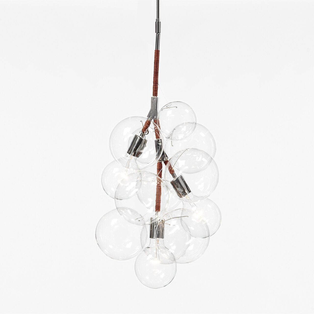 An illuminated bubble chandelier with polished nickel hardware and custom red brown leather detailing hangs in front of a warm gray backdrop.