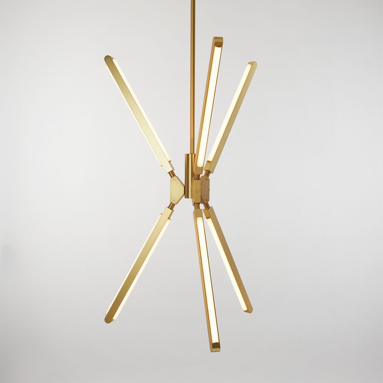 Eye level view of an illuminated Pris Torch chandelier with satin brass metal components