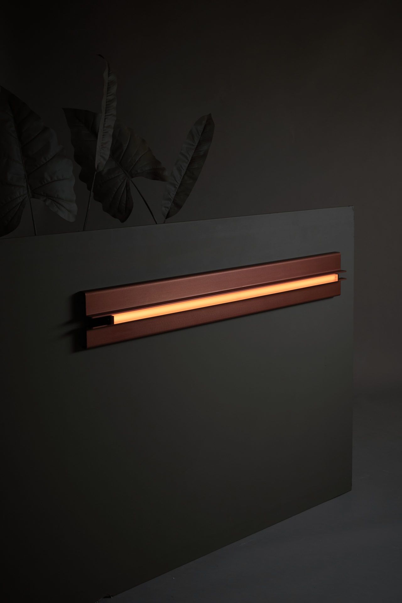 Three quarter view of Pelle’s Glow 04 Sconce in custom anodized bronze with amber lens.