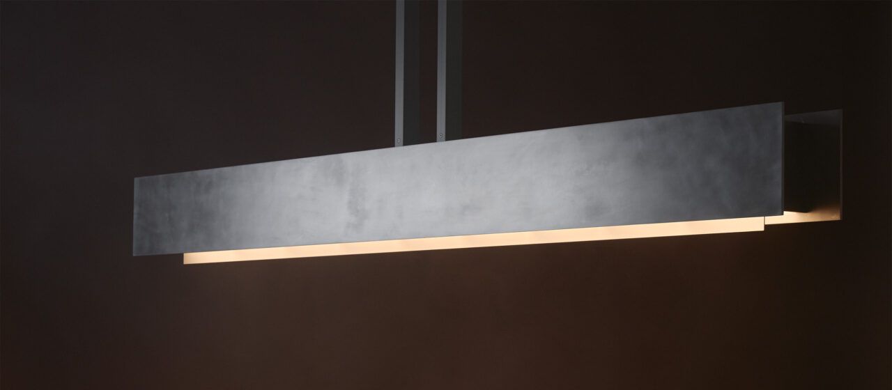 Three quarter view of Pelle’s illuminated Be Patient fixture, made of hand-finished aluminum panels