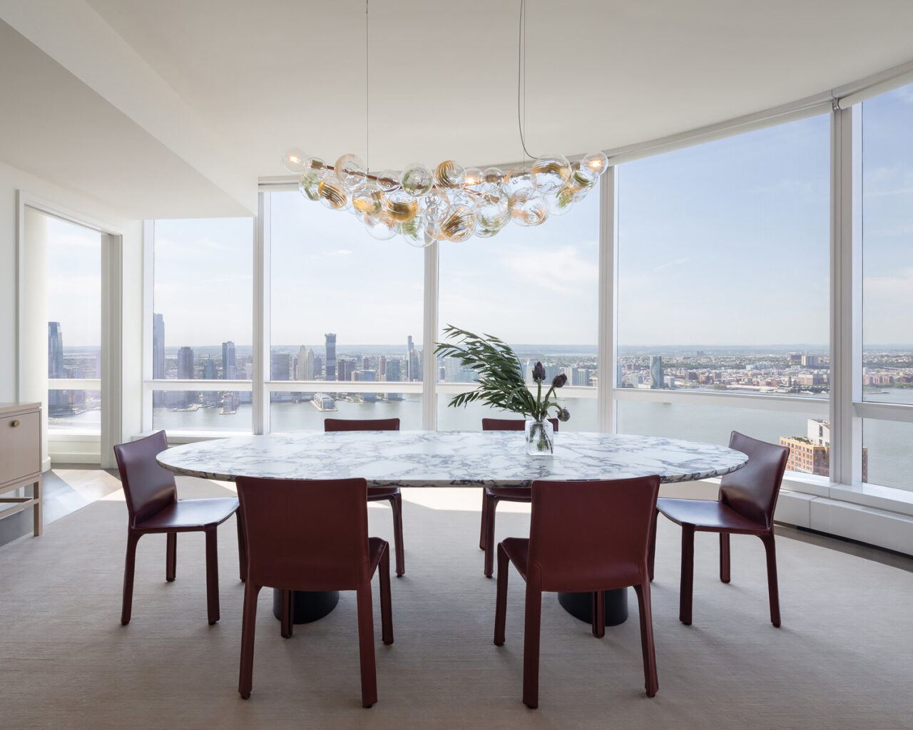 Pelle's Long 62 Bubble Chandelier hangs above the dining table in a modern apartment with skyline views.