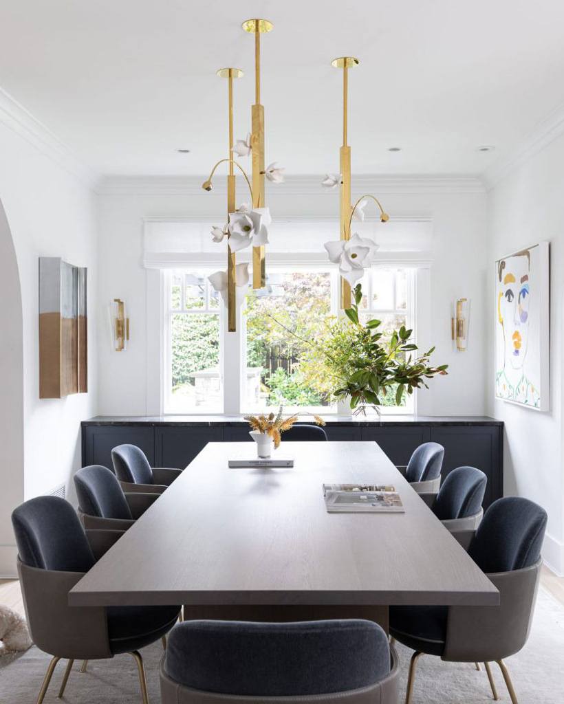 A trio of Pelle's Lure 30 Pendants hang above a dining table in a minimal home with contemporary art pieces.